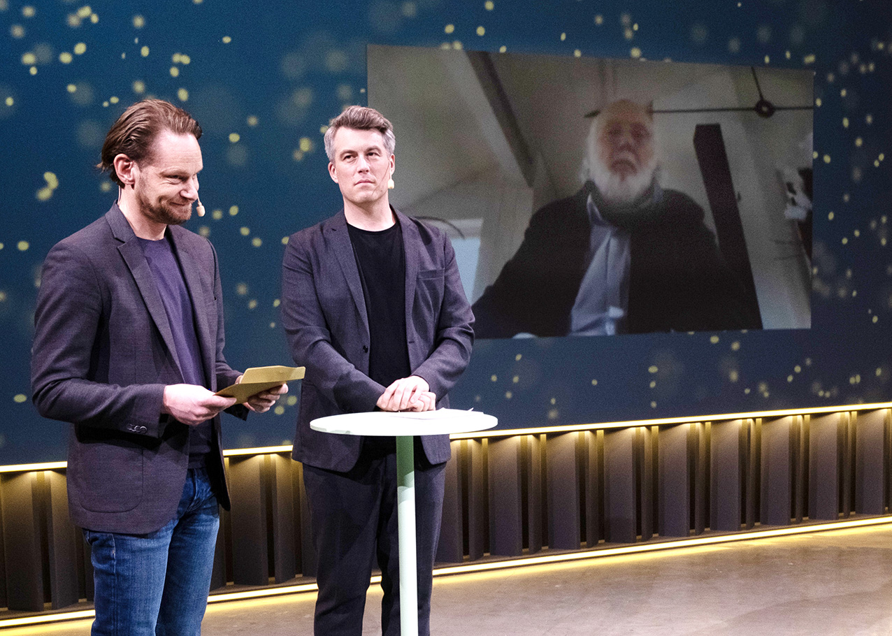 Jonas Bohlin (på skärmen till höger) blir utsedd till hedersmedlem under Arkitekturgalan 2021. Prisutdelare, från vänster, Fredrik Drotte och Tobias Olsson. Foto: Jonas Malmström.