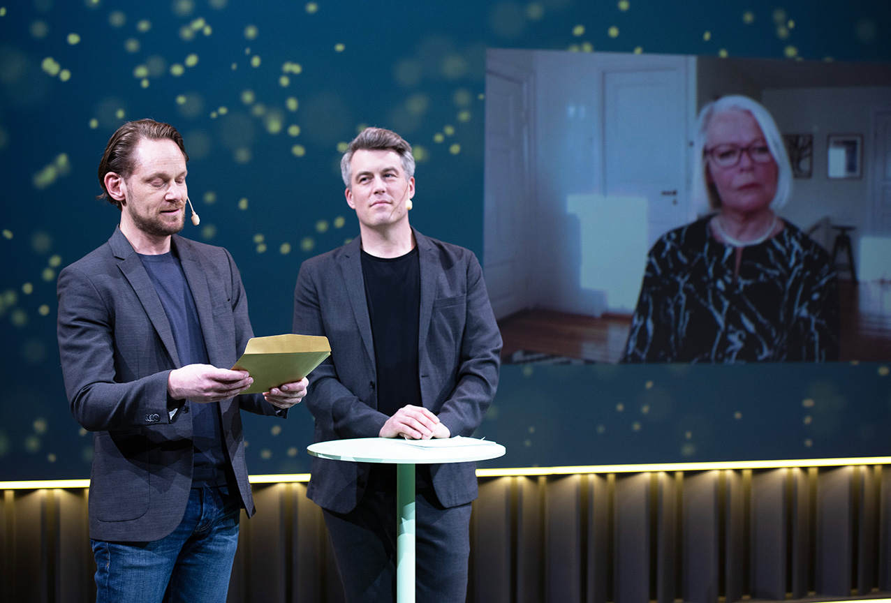 Tiina Sarap (på skärmen till höger) blir utsedd till hedersmedlem under Arkitekturgalan 2021. Prisutdelare, från vänster, Fredrik Drotte och Tobias Olsson. Foto: Jonas Malmström.