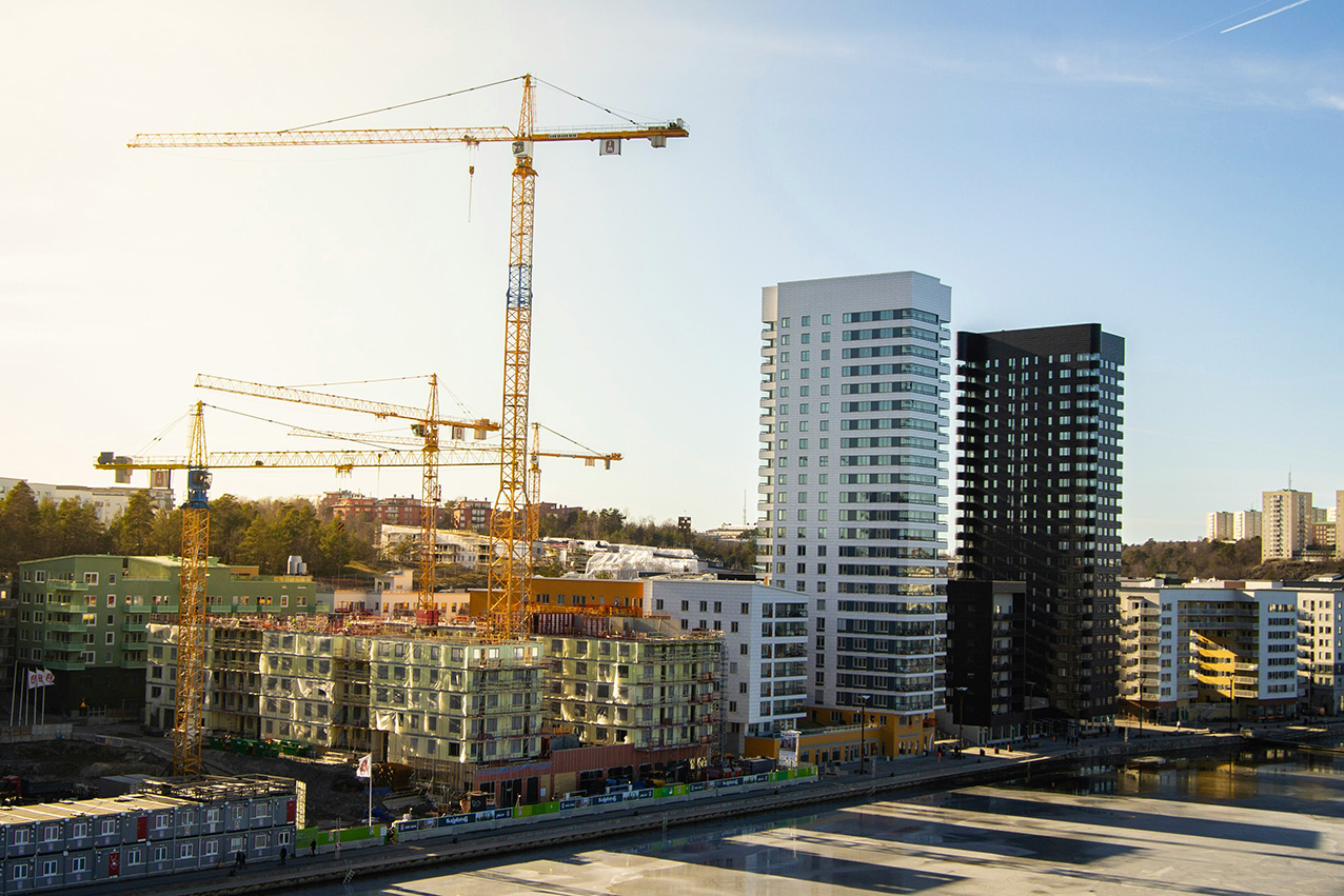 Flygfoto över bostadshus under uppförande vid vatten i Stockholm.