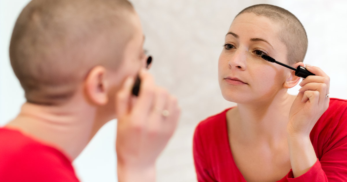 Young adult cancer survivor applying mascara