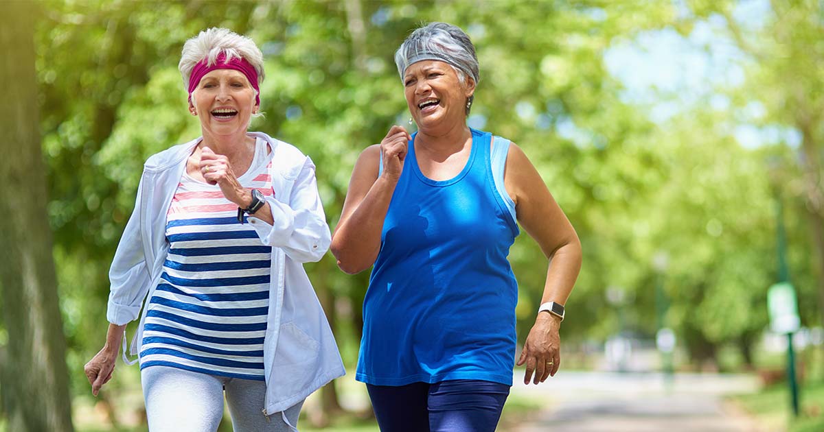 Two senior women speed-walking through park