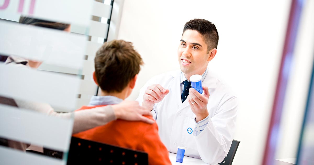 Pharmacist explaining medication to child and his parent