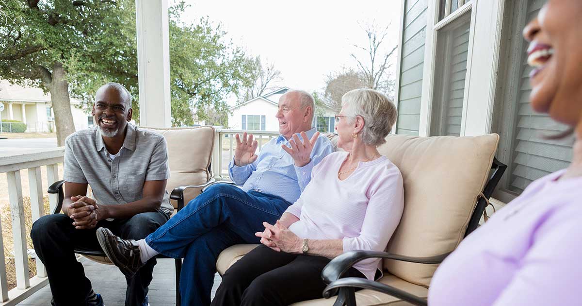 A group of seniors having a lively conversation on a porch