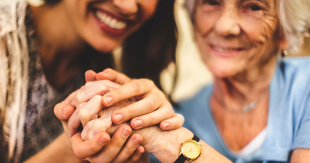 Adult and elderly women holding hands and smiling