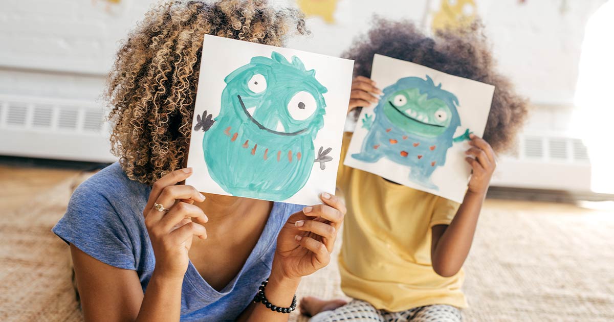 Mom and child holding drawings of cute monsters in front of their faces