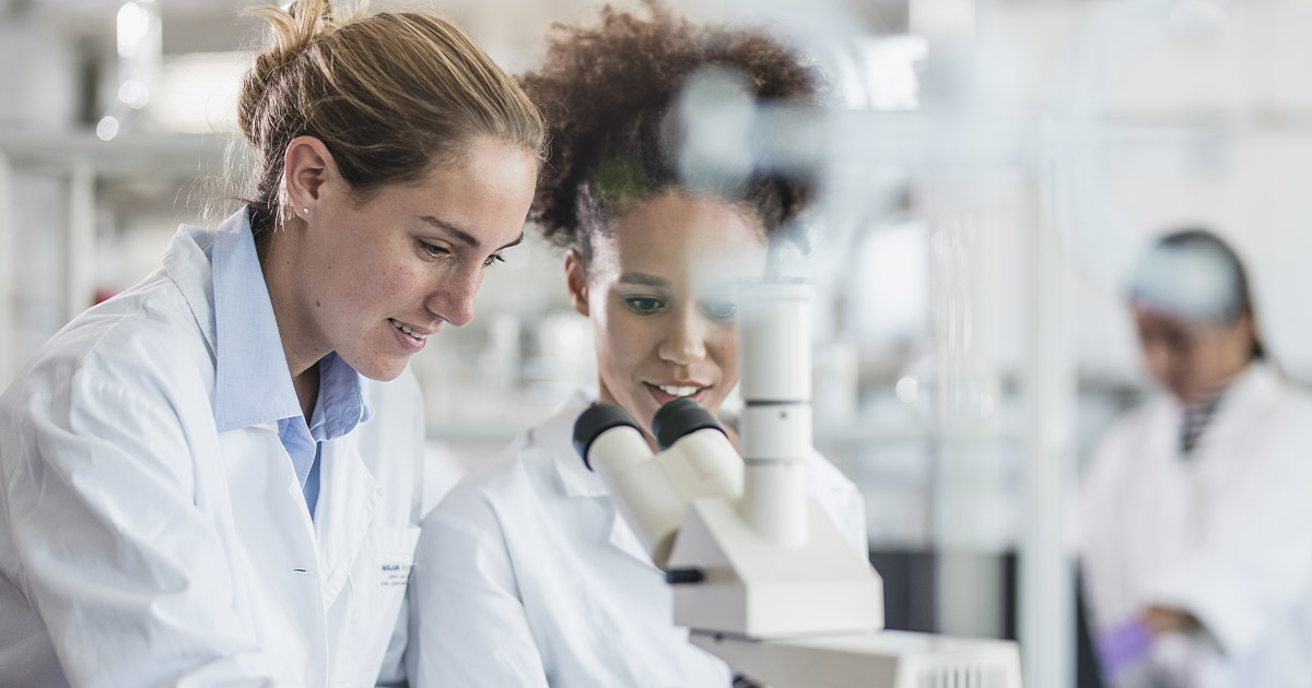 Two female scientists using a microscope