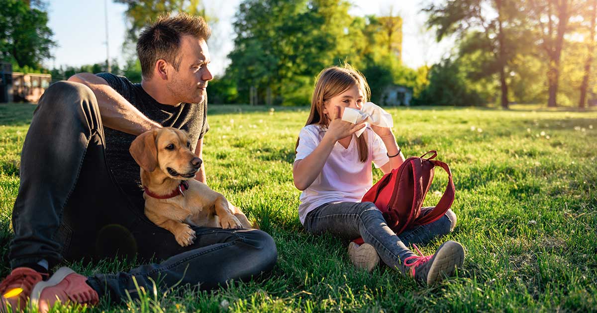 Girl in park with allergies, her dad, and their dog