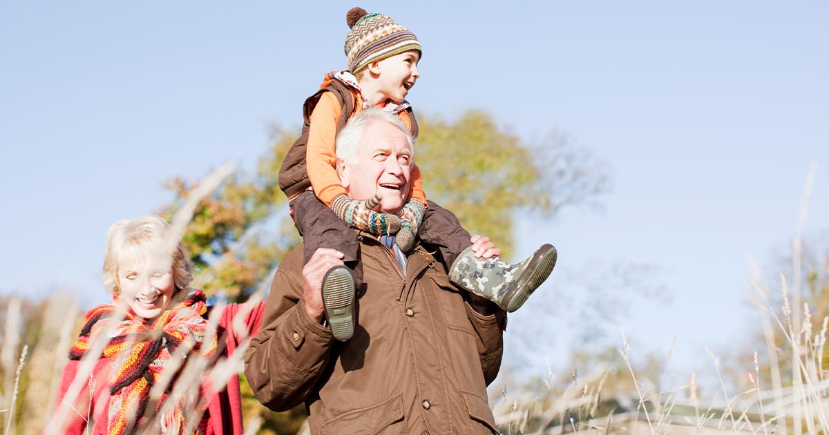 Grandparents walking in a field with their grandson