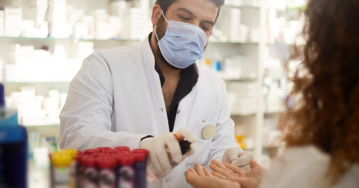 Pharmacist squeezing hand sanitizer into customer's hands