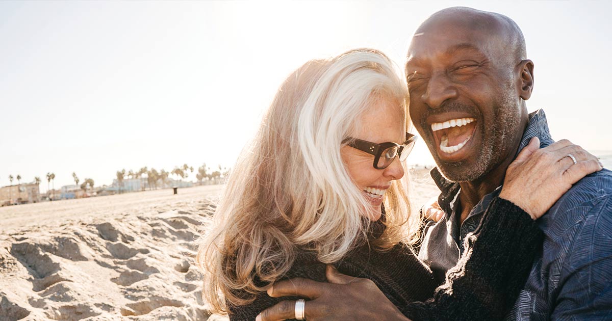 Mature couple laughing and hugging on a beach