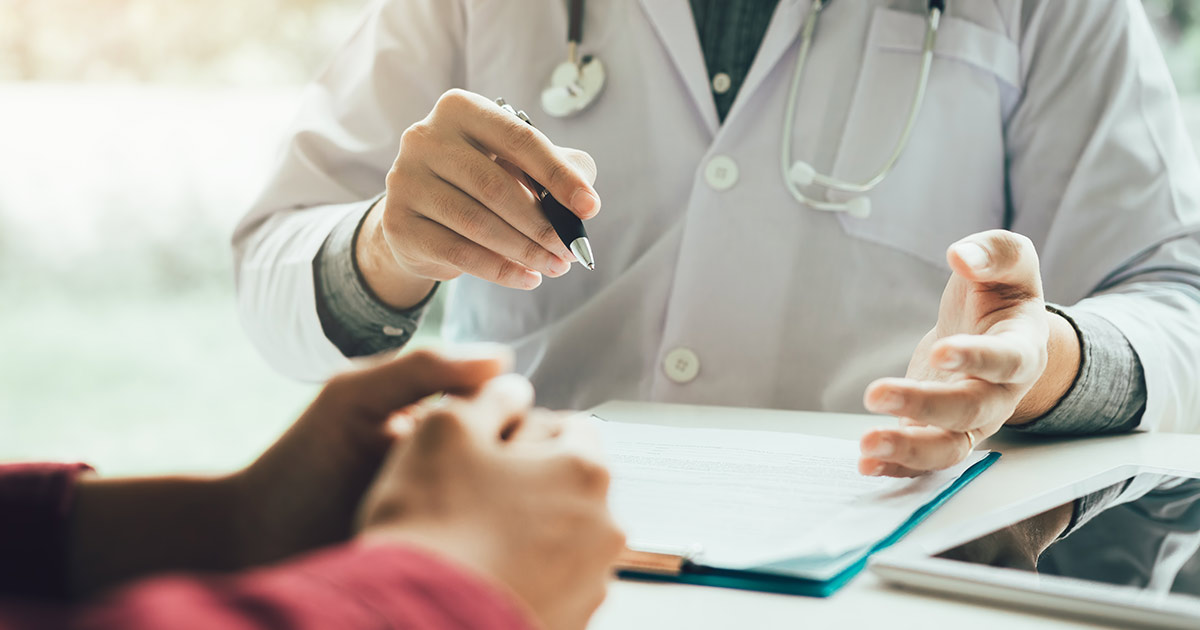 Close-up of a doctor explaining a diagnosis to a patient, showing only their hands