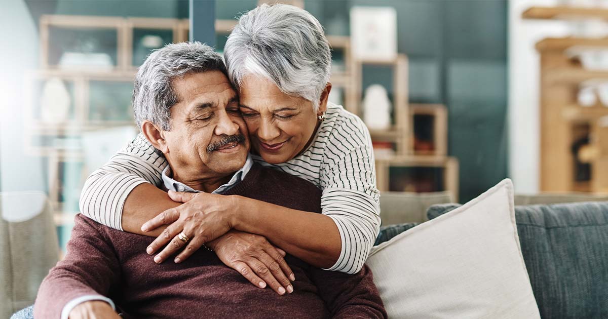 Elderly couple hugging in their home