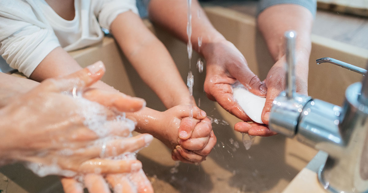 Family washing their hands together with soap and water