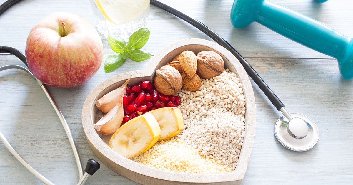 A bowl filled with nutrient rich foods placed in the middle of a stethoscope and dumbell