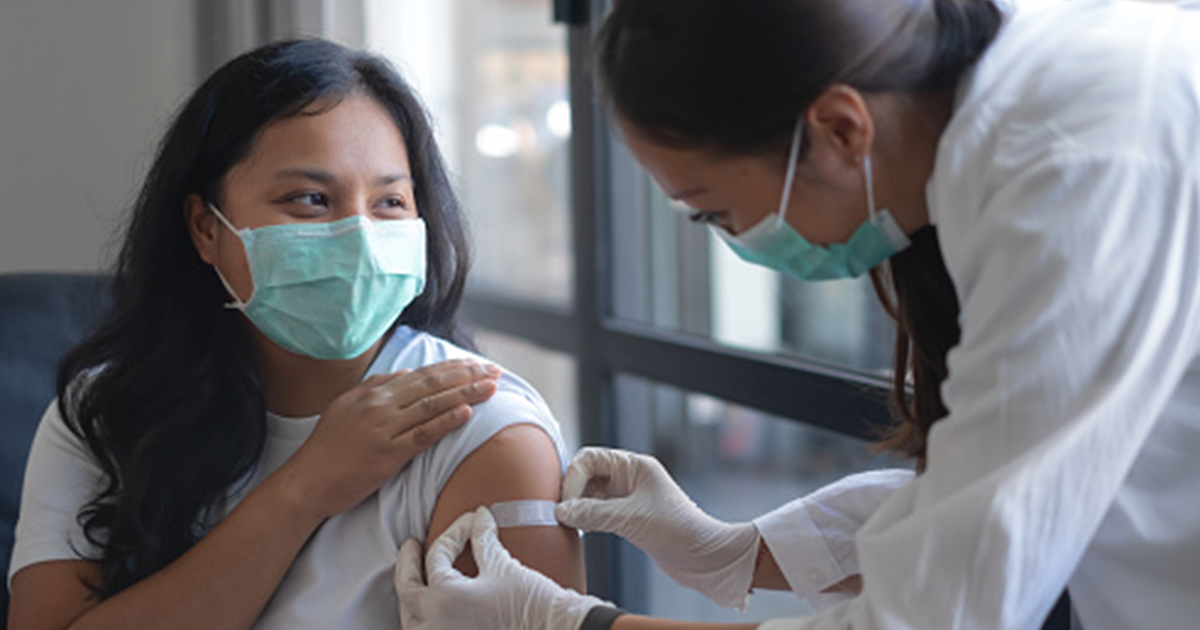 Women putting a band aid on girls arm
