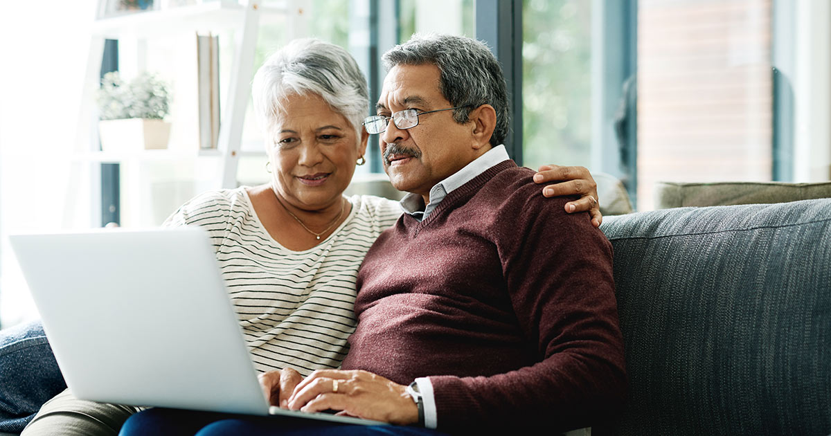 Two elderly people looking at a laptop