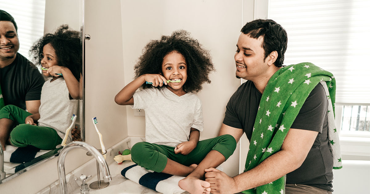 man with daughter brushing teeth