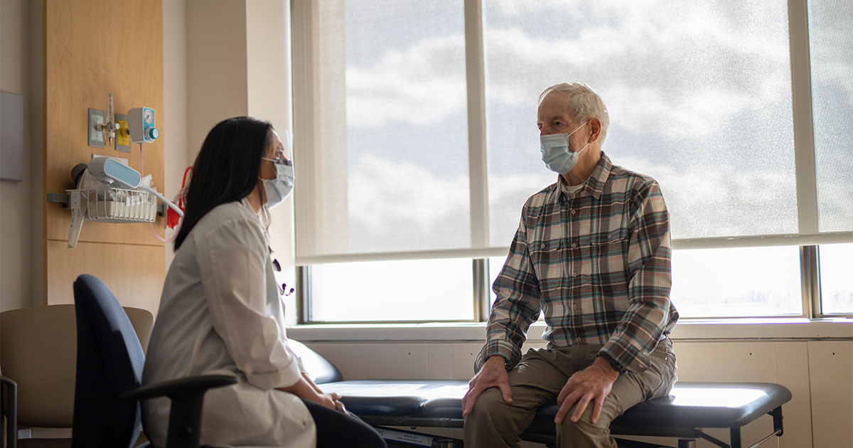 old man with mask talking to doctor