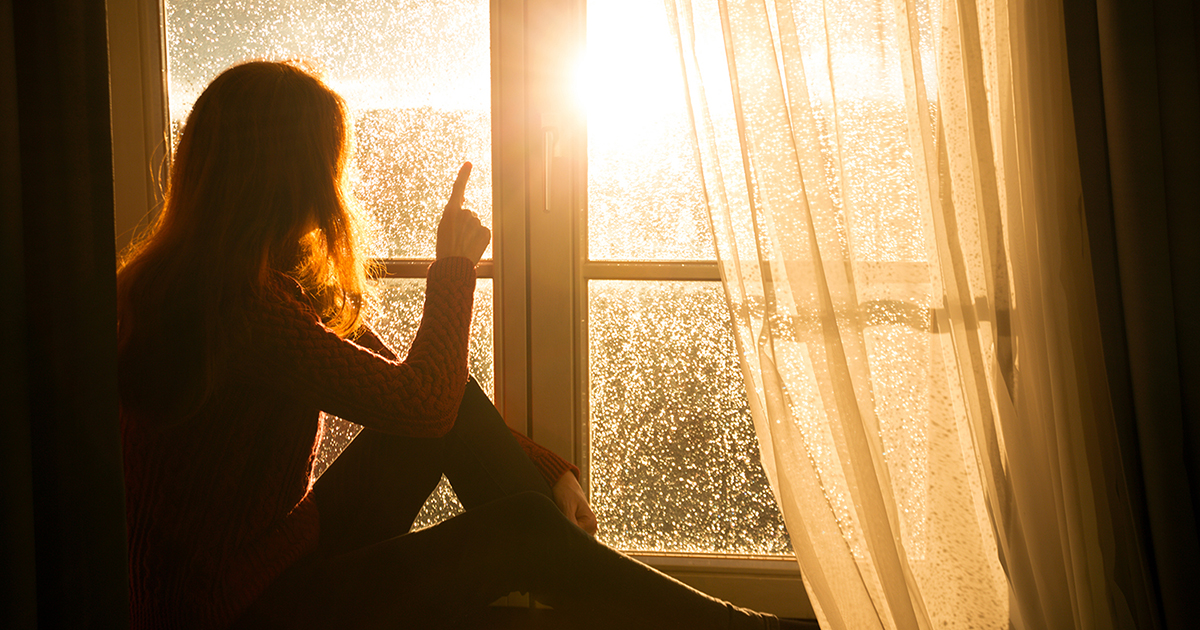 Woman Looking Out Bright Window