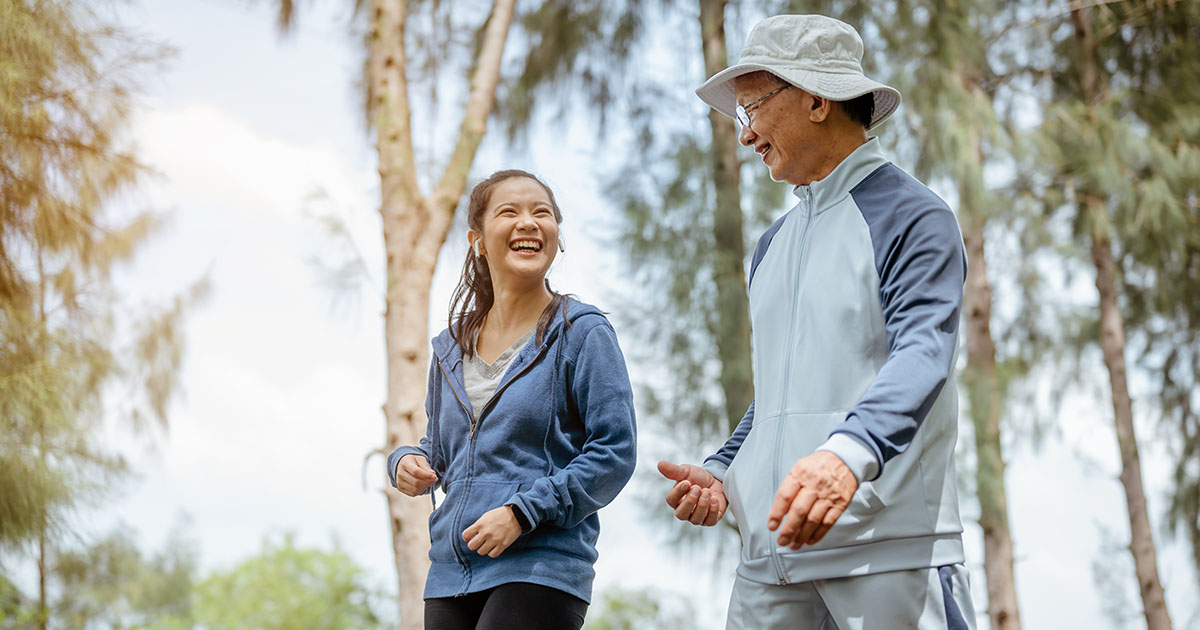 young asian girl and old man laughing in park
