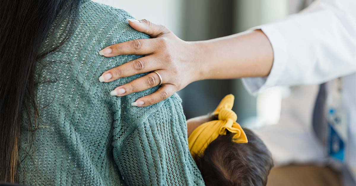 Unrecognizable person touches a mother's shoulder