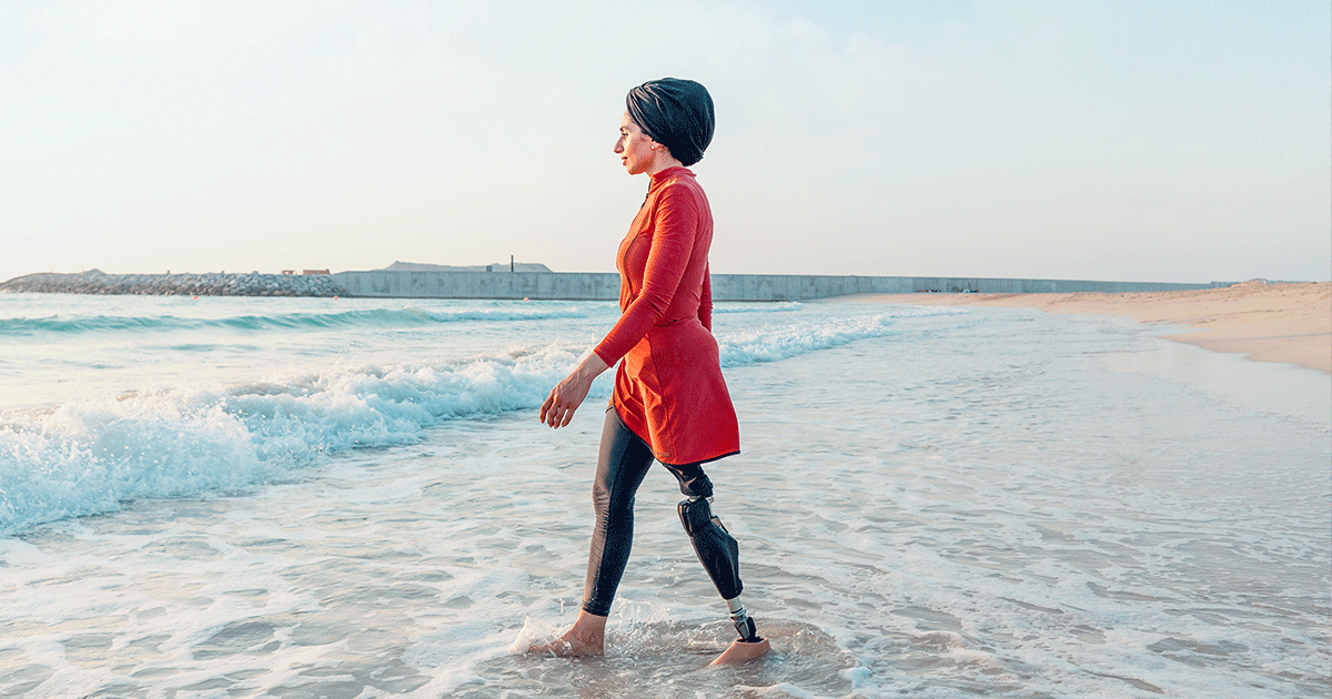 woman with prosthetic leg walking in the ocean