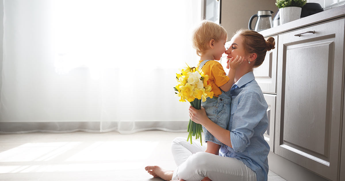 Woman and her toddler sitting in a kitchen and touching noses