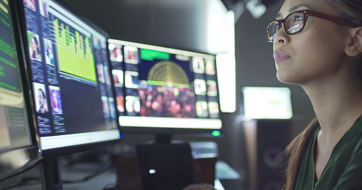 Woman working with multiple computer monitors