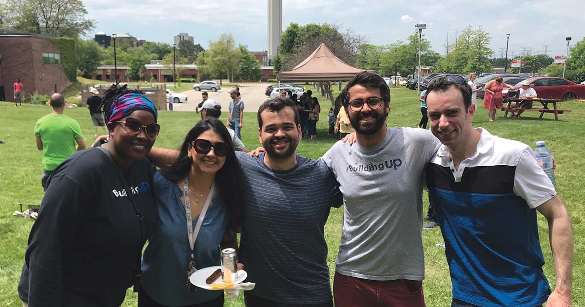 Five smiling people at an outdoors event