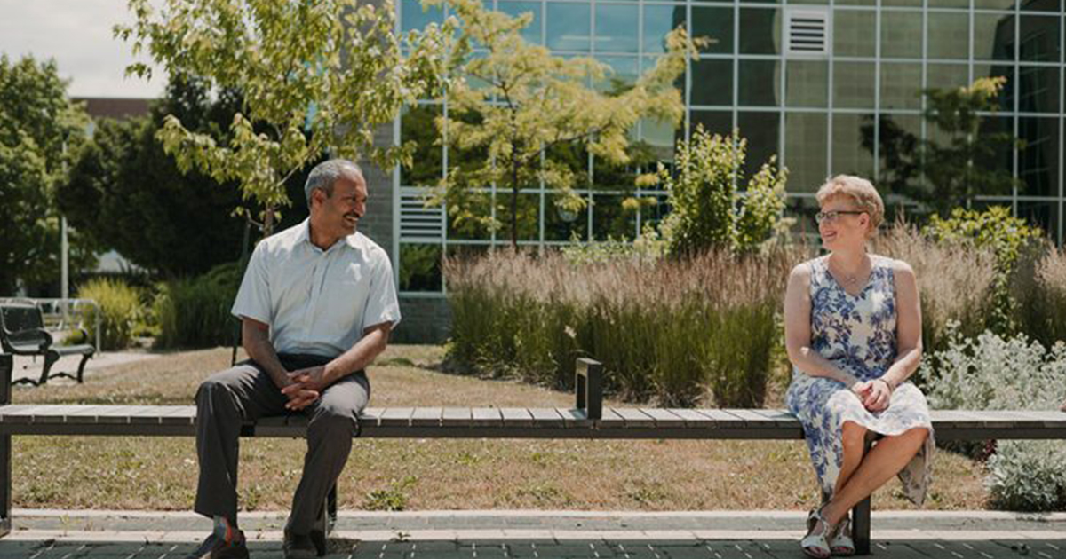 Man and Woman Sitting Across from Each Other on a Bench Enjoying Conversation