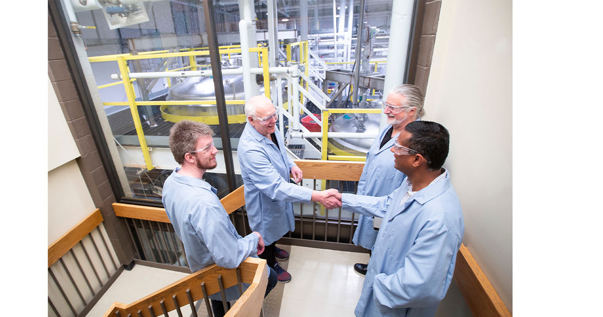 Four Scientists Conversing in a Stairwell Overlooking their Lab
