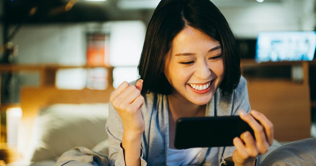 excited asain woman watching something on phone