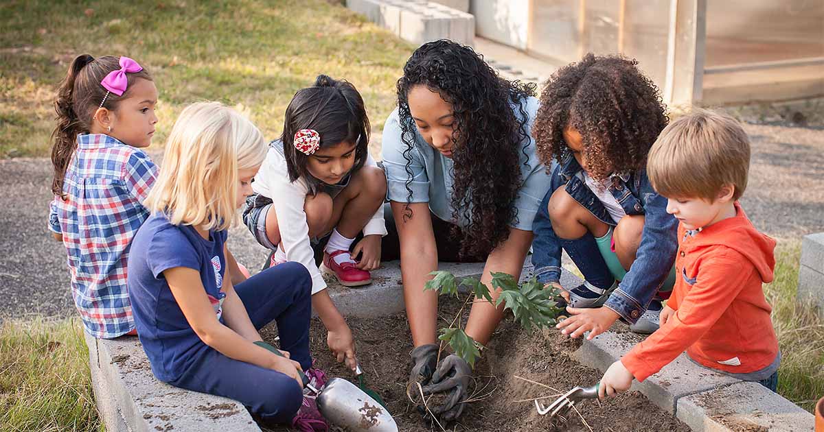 woman showing children how to garden
