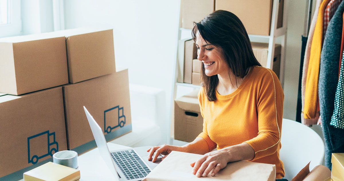 woman in orange top smiling at computer