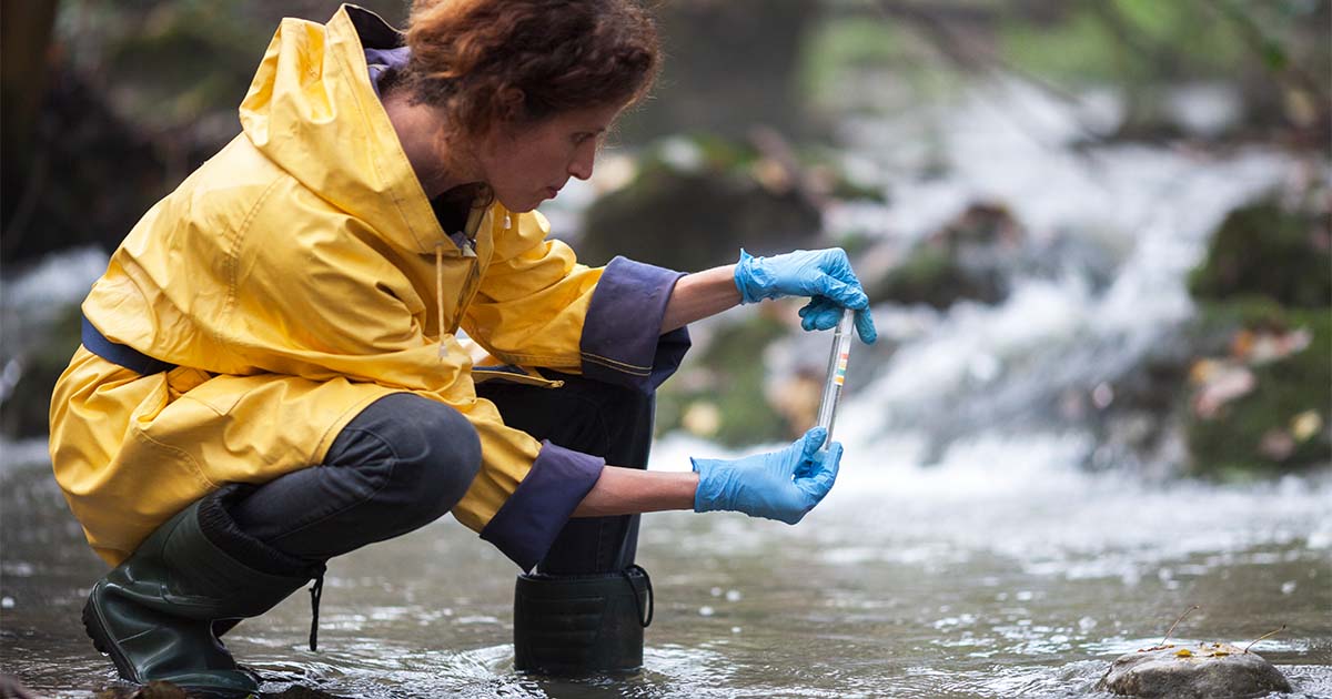 woman in yellow coat examining water