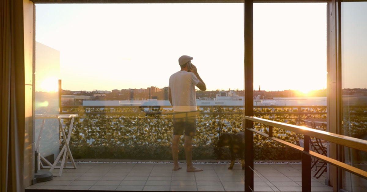 man standing balcony sunset
