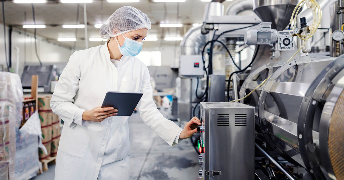 A female milk plant operator holding tablet and adjusting milk processing machine
