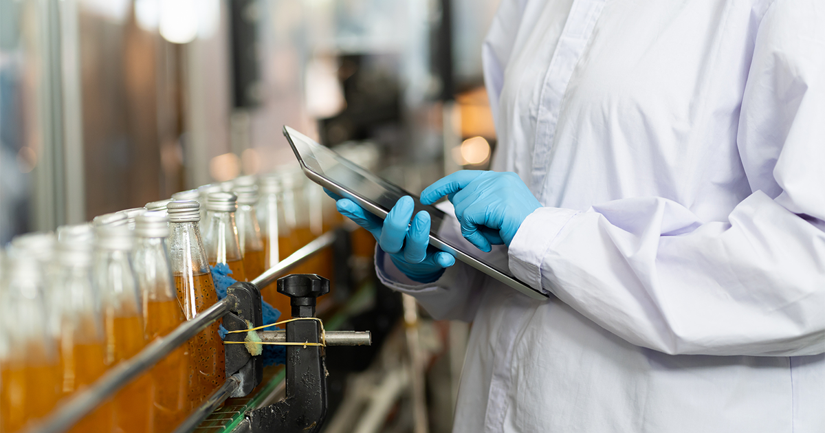 Hands of worker working with digital tablet check product on the conveyor belt in the beverage factory.