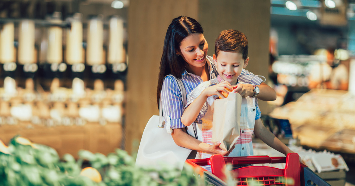 Mother and son buying fruit at grocery store or supermarket - shopping, food, sale, consumerism