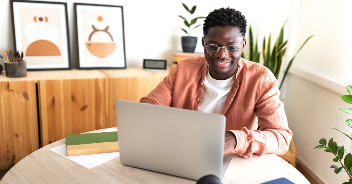 male university student studying at home using laptop.