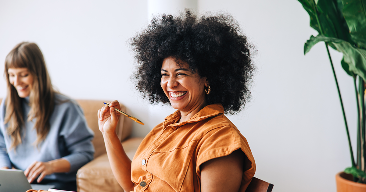 Black businesswoman smiling cheerfully while sitting in a meeting