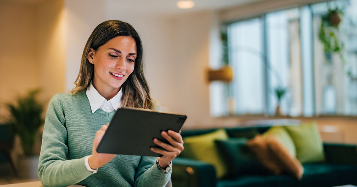 Adult businesswoman looking for a new job over the digital tablet, sitting in the living room, elegantly dressed