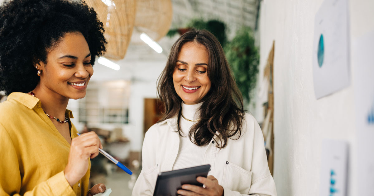 Female entrepreneurs using a tablet together as they brainstorm in an office