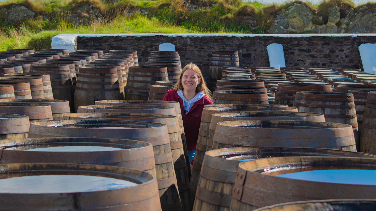Young woman between whiskey barrels and casks