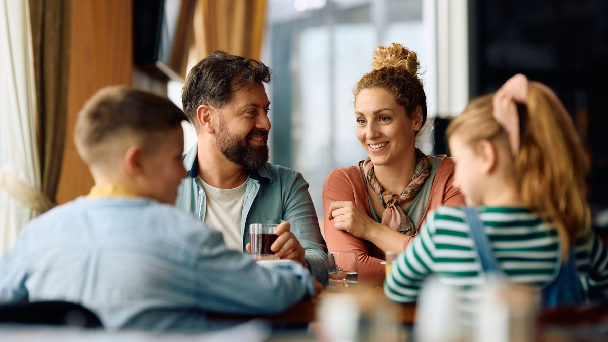 Happy family talking while eating at dining table in restaurant