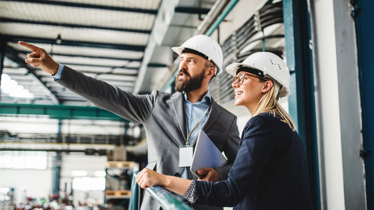 A portrait of an industrial man and woman engineer with tablet in a factory, working