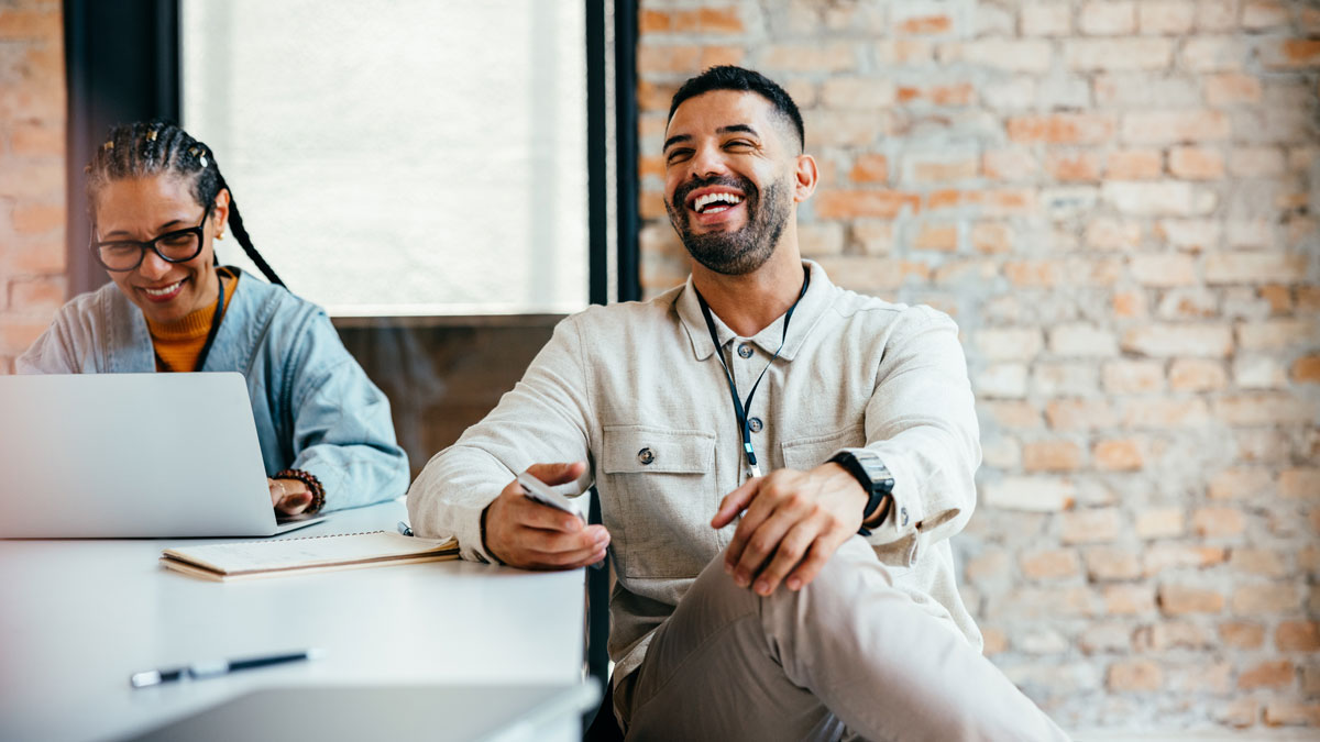 Relaxed businessman enjoying a casual office discussion with a colleague, showcasing a positive and collaborative work environment