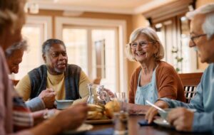 Happy senior woman talks to her friends during lunch in residential care home.