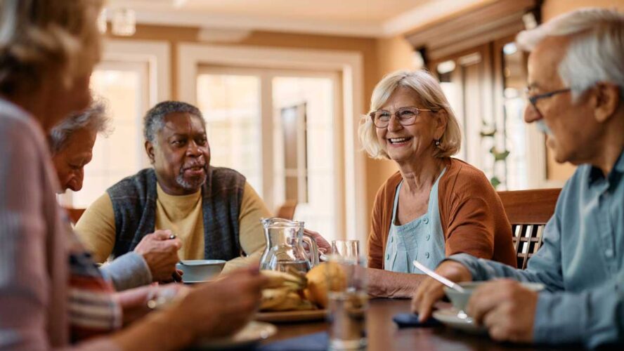 Happy senior woman talks to her friends during lunch in residential care home.