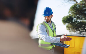 Engineer, man and clipboard for solar power at construction site with business people, point and talk. Person, technician and outdoor for presentation, renewable energy solution and sustainability